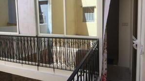 A balcony with a wrought iron railing, a view of a building, and a door with a curtain. - Beautiful Apartment for those looking for Calm (Tanger)