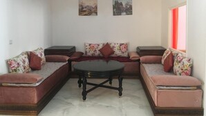 A living room with a sectional sofa, a coffee table, and two wall-mounted paintings. - Beautiful Apartment for those looking for Calm (Tanger)