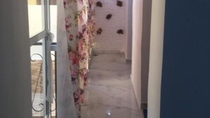 A narrow hallway with a marble floor, a glass door on the left, and a floral curtain. - Beautiful Apartment for those looking for Calm (Tanger)