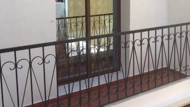 A balcony with a wrought iron railing, a window with a dark frame, and two wall-mounted light fixtures. - Beautiful Apartment for those looking for Calm (Tanger)