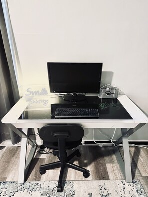 Un escritorio con computadora, monitor, teclado y silla.