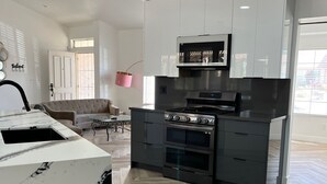 A modern kitchen with a built-in oven, a microwave, and a large island with a sink. - The Stylish Stay in Hesperia (Hesperia)