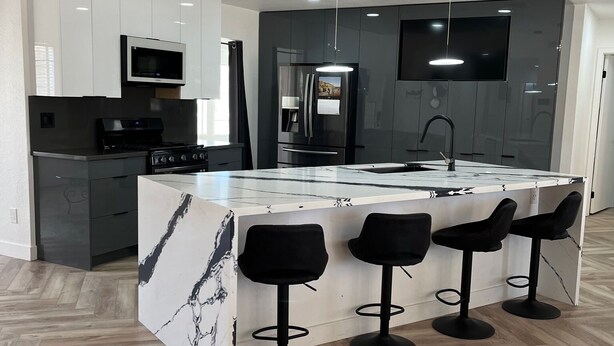 A modern kitchen with a central island, bar stools, and built-in appliances. - The Stylish Stay in Hesperia (Hesperia)