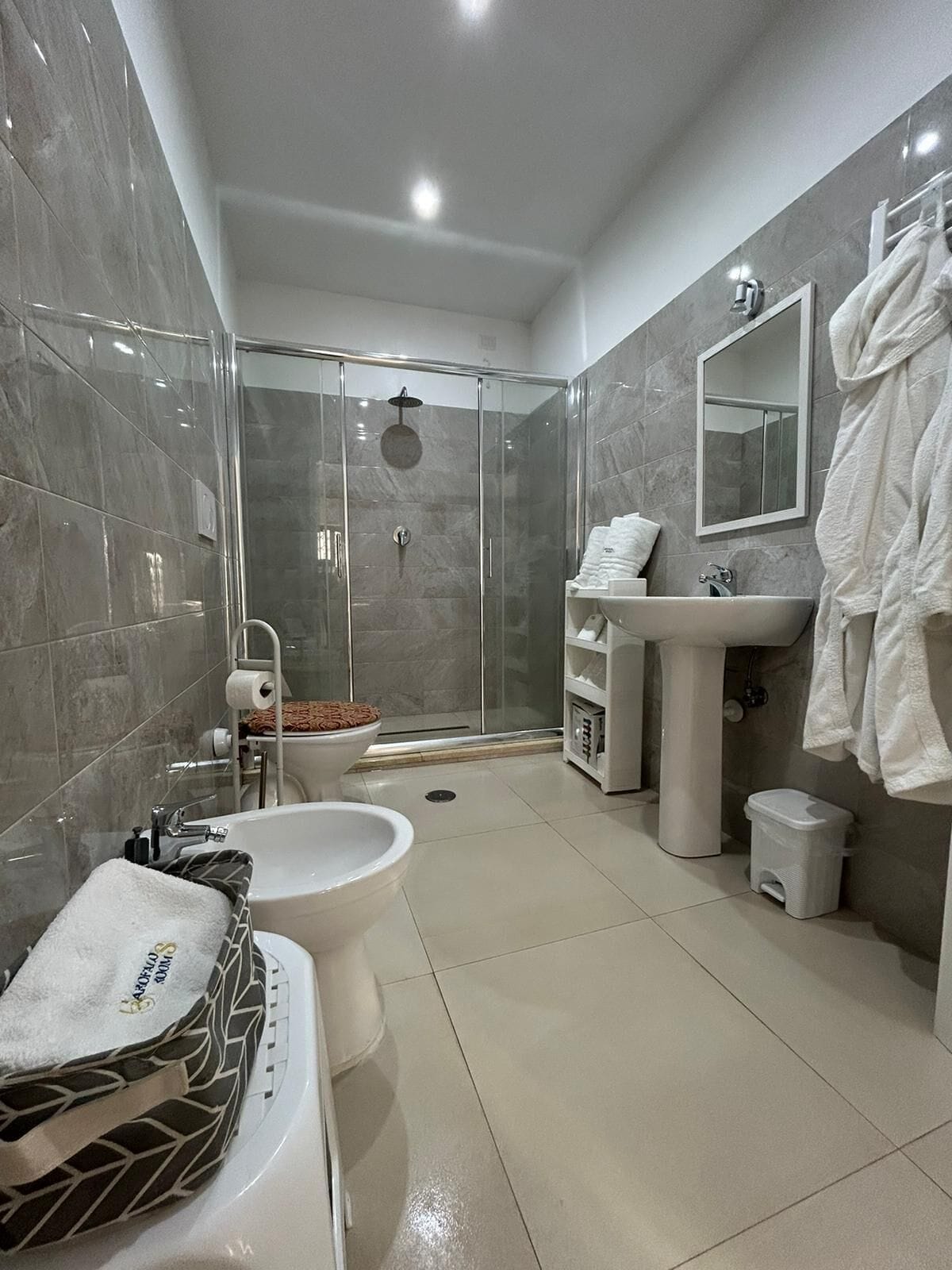 A modern bathroom with a glass-enclosed shower, a white sink, and a toilet.