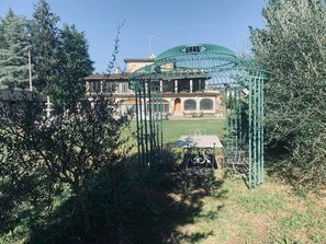 Un giardino con un gazebo, una fontana e un edificio sullo sfondo.