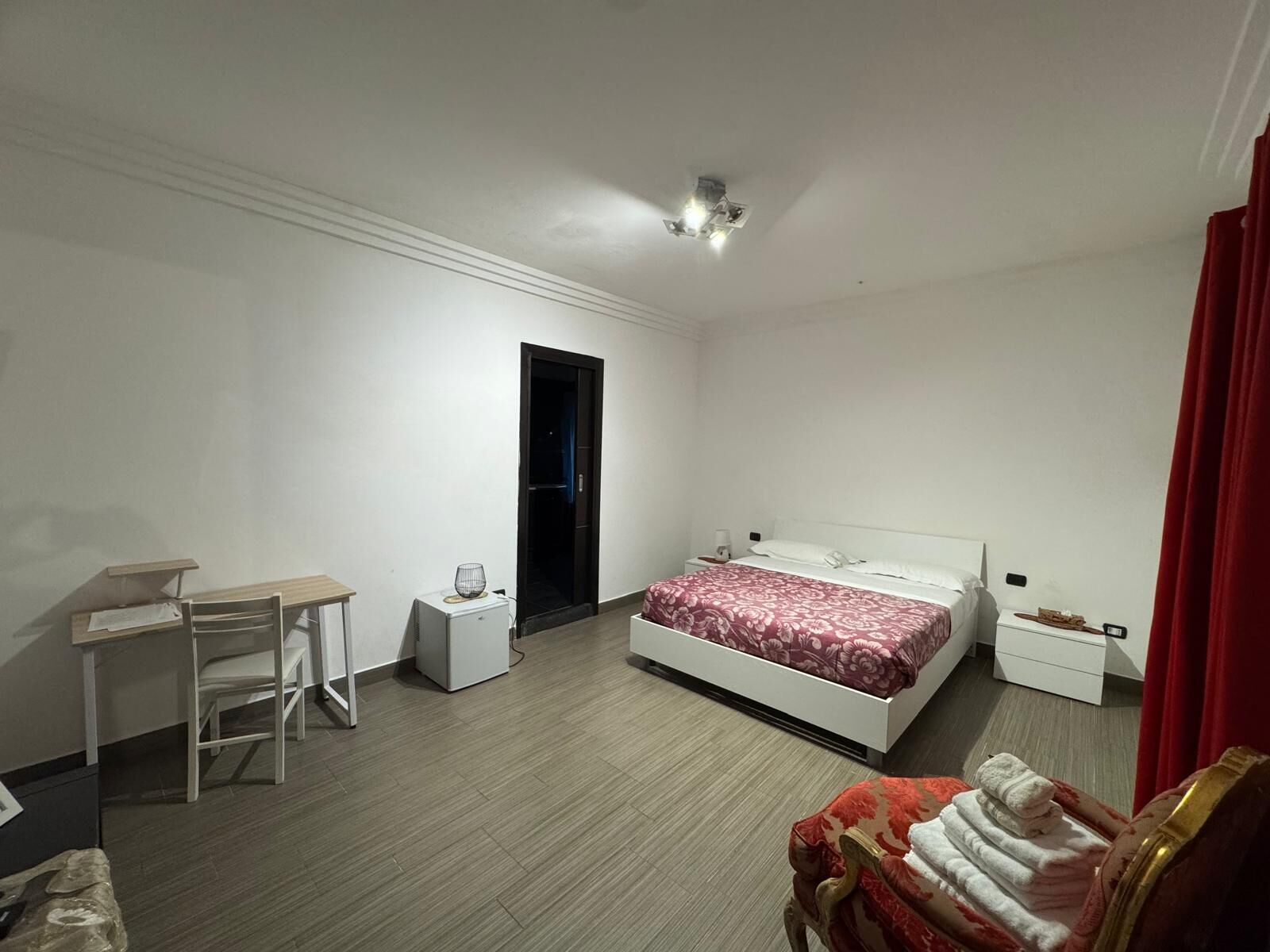 A bedroom with a bed, a desk, a chair, a heater, and a wardrobe.
