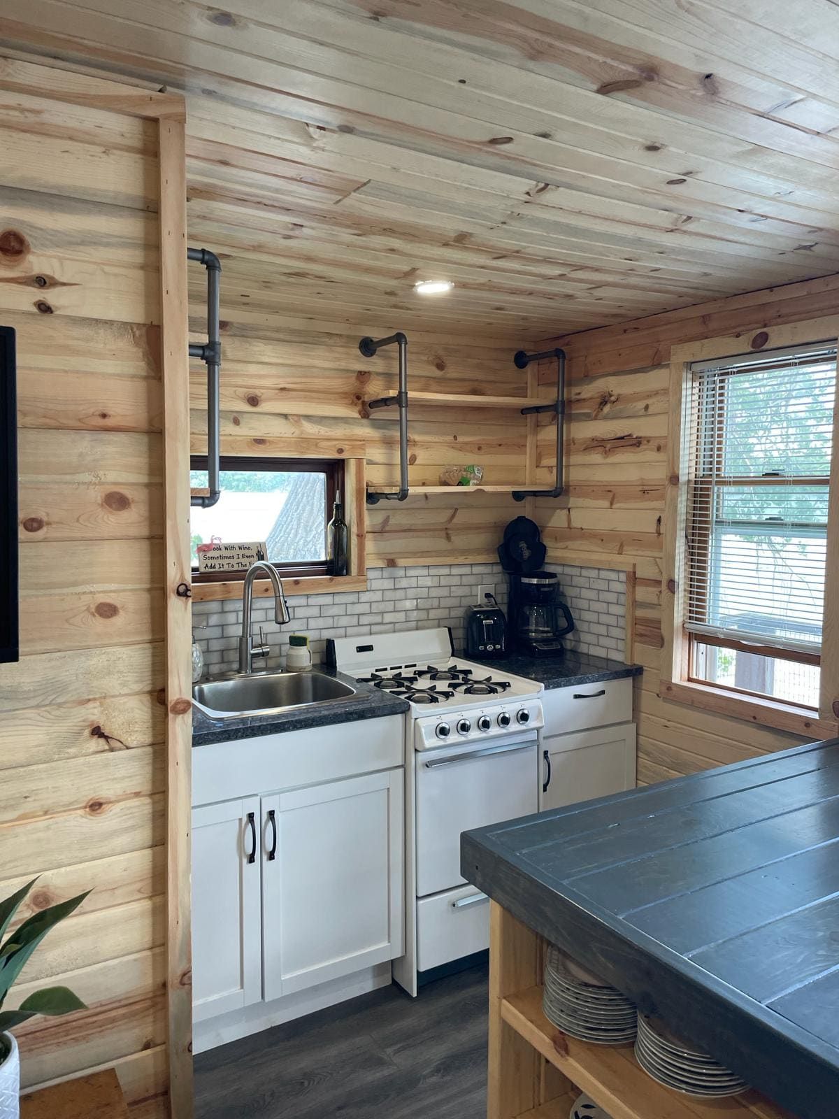 A compact kitchen with a gas stove, sink, and white cabinets.
