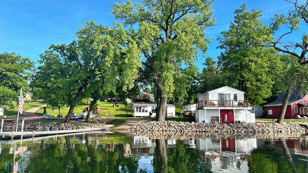 A lakeside property with a dock, a playground, and several cabins.