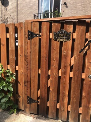 A wooden gate with a house number sign.