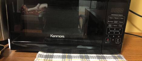 Een Kenmore magnetron op een houten tafel met een geruit tafelkleed.