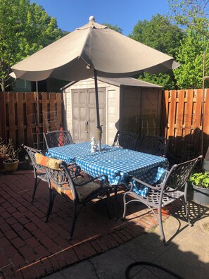 A patio with a table and chairs under a large umbrella, surrounded by a wooden fence and potted plants. - Bedroom with private full bathroom, linen and towels are provided. (Chicago)