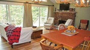 A cozy living room with a fireplace, a dining table, and comfortable seating. - Tranquil Privacy (Rhinelander)