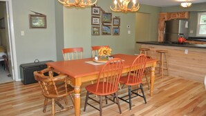 A dining area with a wooden table and chairs, a chandelier, and framed pictures on the wall. - Tranquil Privacy (Rhinelander)