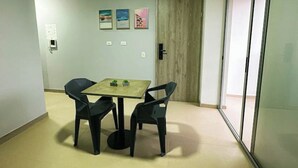 A small room with a table and two chairs, a wooden door, and a sliding glass door. - Moderno y Acogedor Apartamento Medellín Laureles (Medellín)