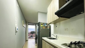 A modern kitchen with a gas stove, a refrigerator, and a sink. - Moderno y Acogedor Apartamento Medellín Laureles (Medellín)