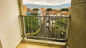 A balcony with a view of a cityscape, including buildings and a distant mountain range. - Moderno y Acogedor Apartamento Medellín Laureles (Medellín)
