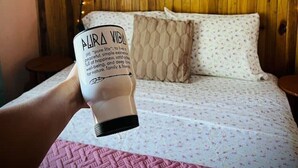 A bedroom with a wooden headboard, a bed with patterned bedding, a pillow, and a sign with a quote. - Beautiful & Cozy Casa Aire, Near Lake Arenal (Nuevo Arenal)