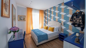 Moderni hotellihuone, jossa on sänky, yöpöytä ja työpöytä tuolilla.