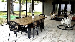A covered patio with a wooden table and chairs, a ceiling fan, and a hanging chair. - Your Forever Home (Lutz)