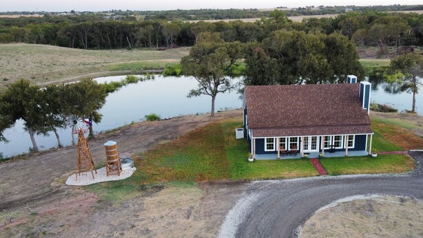 Uma casa com varanda e um pequeno lago ao fundo.