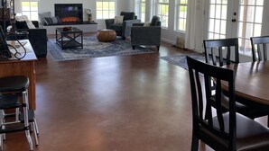 Uma sala de estar ampla com lareira, janelas grandes e ventiladores de teto.