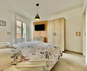 A bedroom with a bed, a wardrobe, a TV, and a pendant light.
