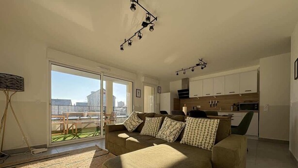 A spacious living room with a sofa, a dining area, and a kitchen. - Alba (Laxou)