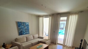 Un salon avec un canapé beige, une table basse en bois et un tableau accroché au mur.