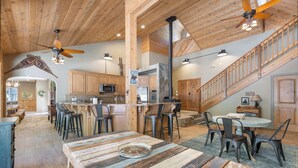 Una cocina amplia con armarios de madera, una isla central y taburetes de bar.