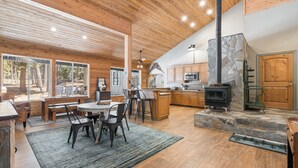 Una cocina amplia con chimenea de piedra, armarios de madera y una zona de comedor con mesa y sillas.