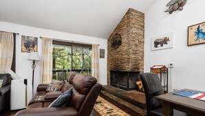A cozy living room with a leather sofa, a fireplace, and a dining table.