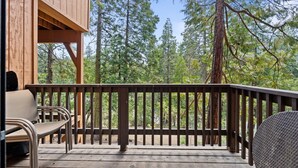 A wooden deck with a railing, a bench, and a chair.