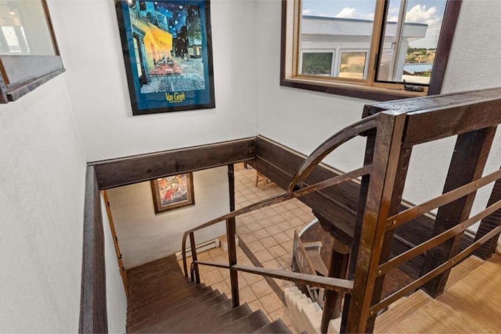 Eine Treppe mit Holzgeländer und Blick auf einen Raum mit einem Gemälde an der Wand.
