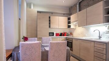 A modern kitchen with wooden cabinets, a dining table with patterned chairs, and a built-in microwave.