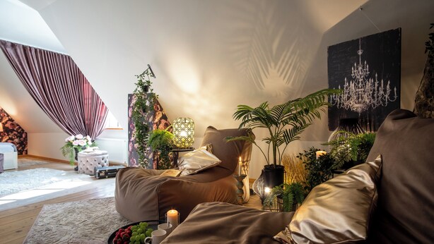 Ein gemütliches Wohnzimmer mit einem braunen Sofa, einem kleinen Beistelltisch mit einer Kerze und einer Obstschale.