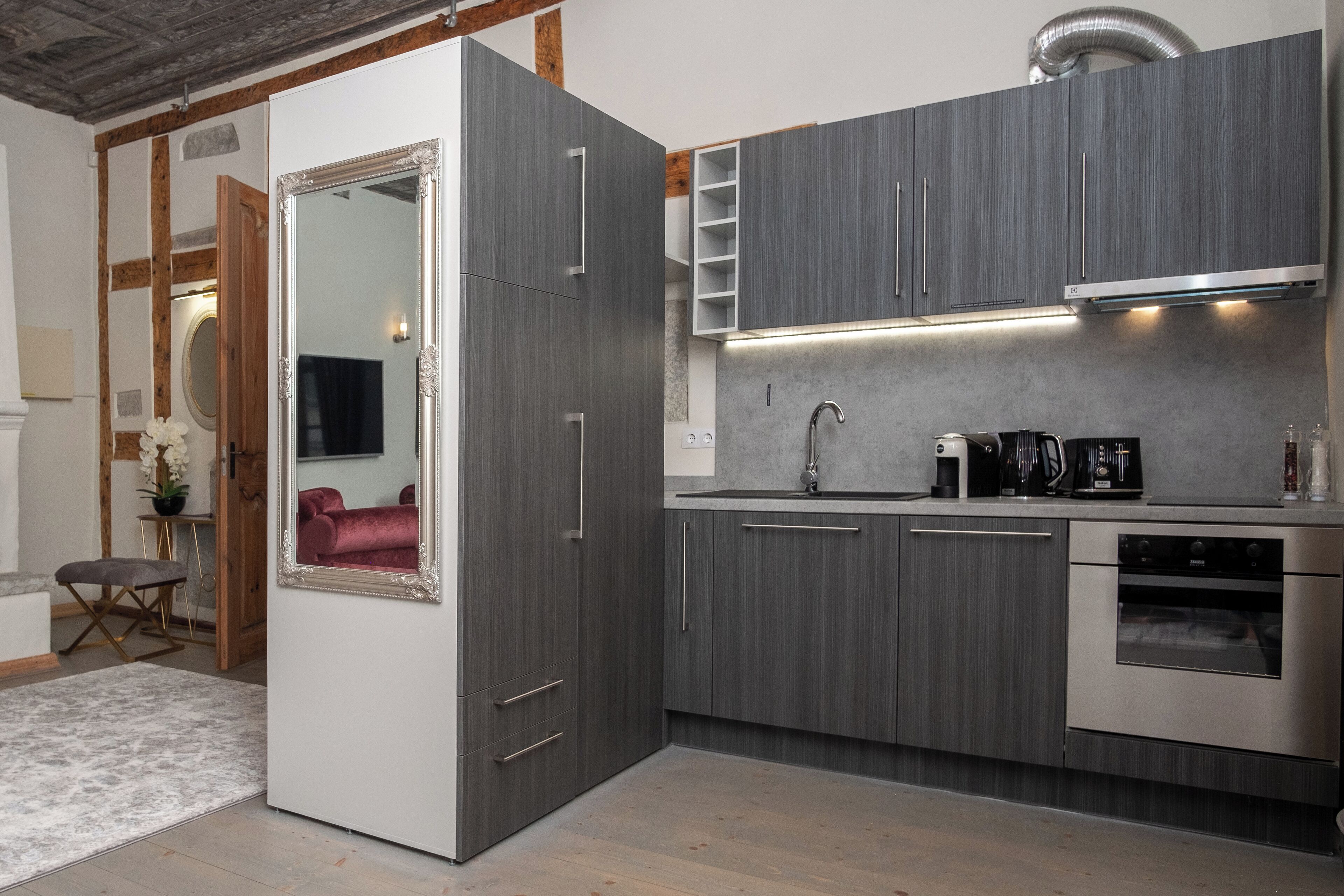 A modern kitchen with grey cabinets, a stainless steel oven, and a built-in microwave.