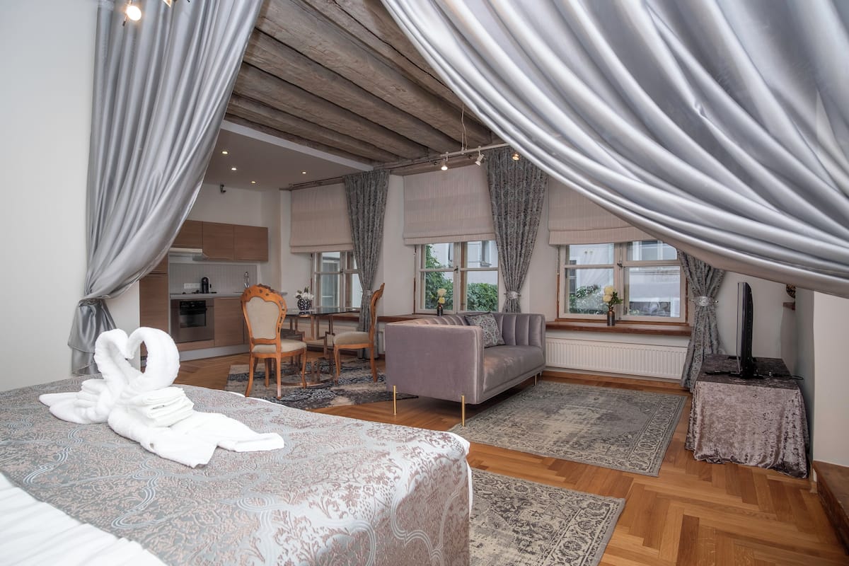 Ein Schlafzimmer mit einem großen Bett, einer Couch, einem Essbereich und einer Küche im Hintergrund.