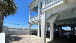 A wooden deck with outdoor seating and a view of the beach. - A Wave From it All (Corpus Christi)