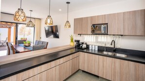 A modern kitchen with wooden cabinets, a black countertop, and pendant lights. - 4BR Private Sanctuary with Pools and Gym (San Miguel de Allende)