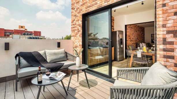 Een terras op het dak met een bank, een kleine tafel en een eethoek met stoelen.