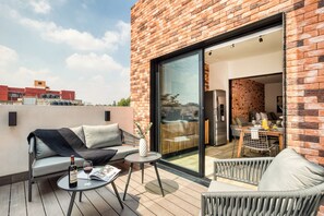 A rooftop terrace with a sofa, a small table, and a dining area with chairs. - ULIV Roma Norte (Mexico City)