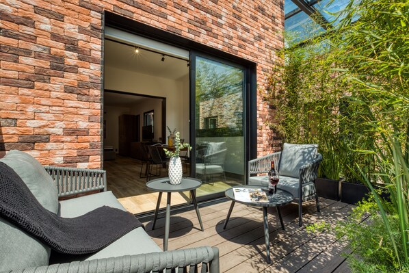A patio with outdoor furniture, a brick wall, and a glass door leading to an interior space. - ULIV Roma Norte (Mexico City)