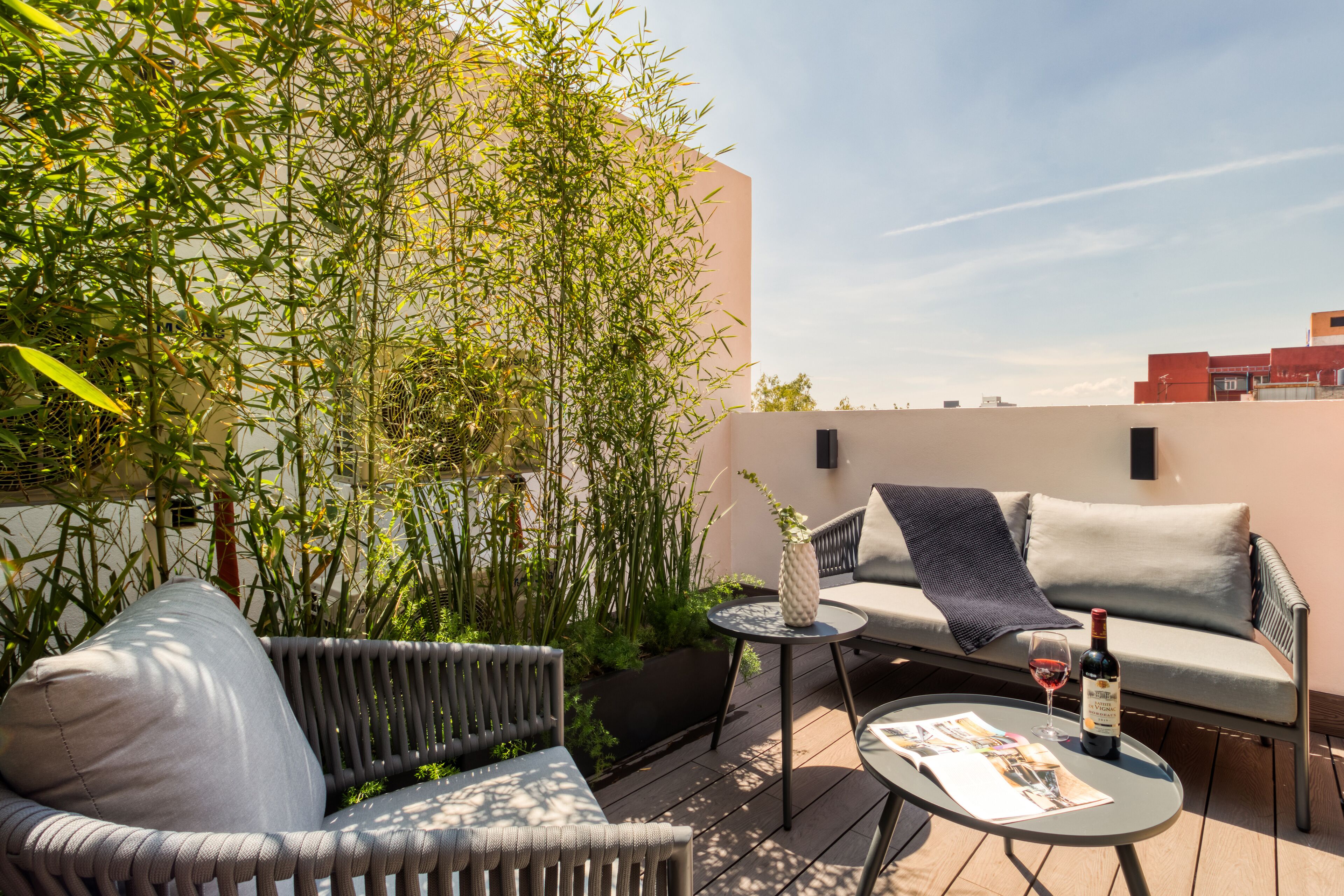 A rooftop terrace with a sofa, a small table, and a wine bottle.
