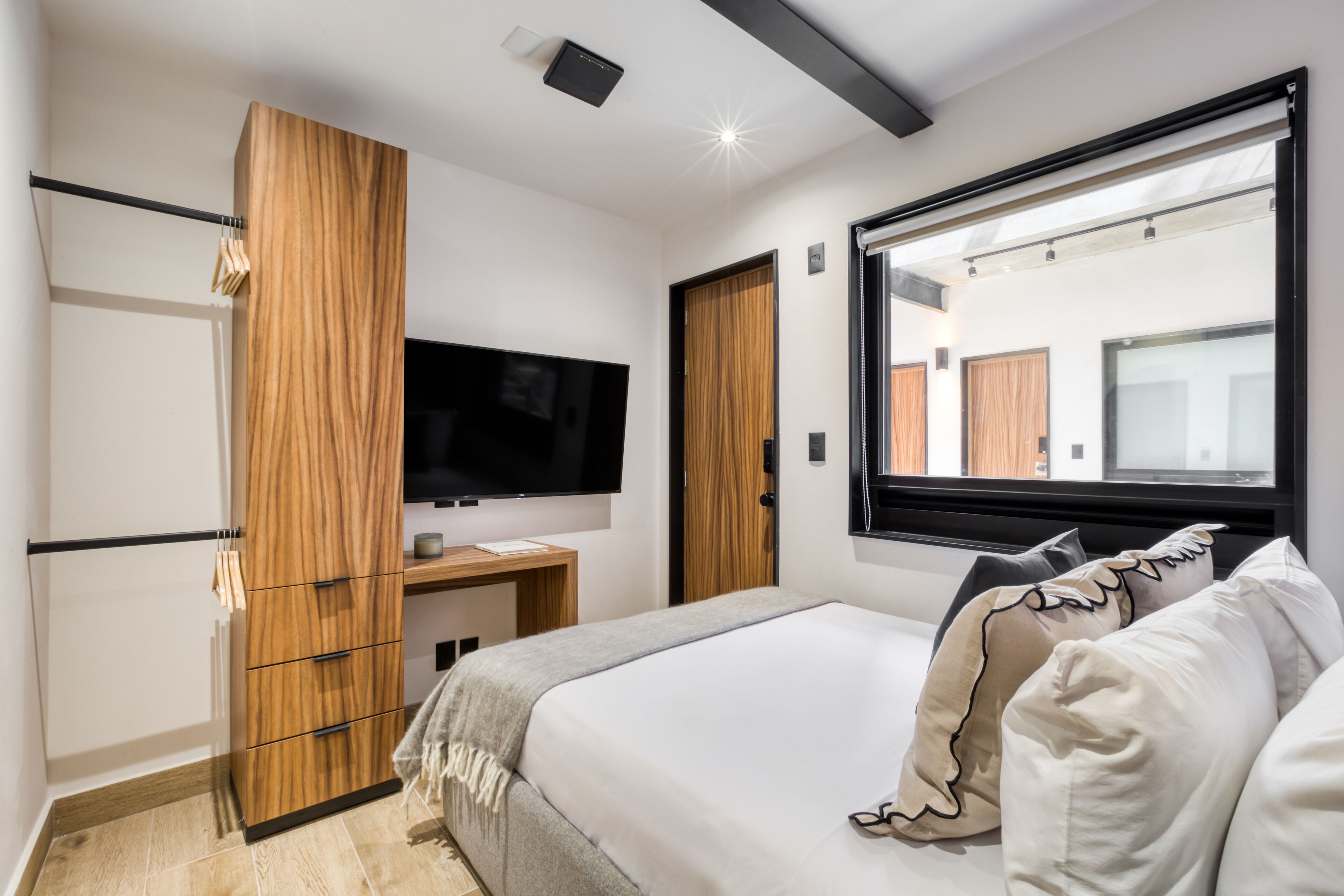 Ein modernes Schlafzimmer mit Bett, Fernseher, Kleiderschrank und Fenster mit Blick.