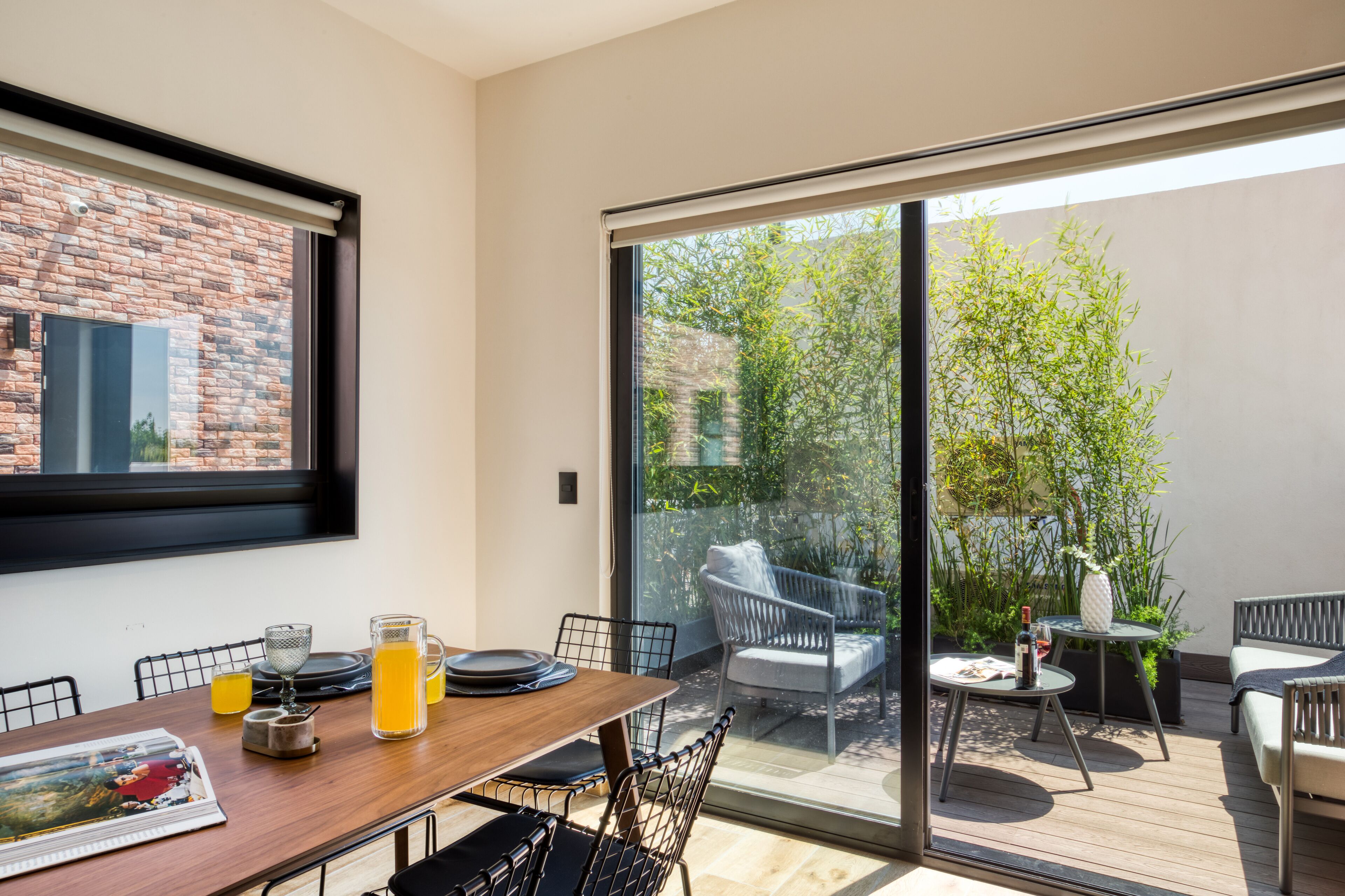 A dining area with a wooden table, chairs, and a glass partition.