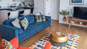 Ein modernes Wohnzimmer mit einem blauen Sofa, einem roten Sessel und einem Couchtisch mit Kerzen.
