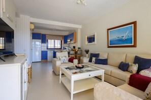 A modern living room with a sofa, coffee table, and a painting of a sailboat.