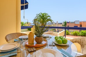 A dining table set outdoors with plates, glasses, and a plate of green apples.