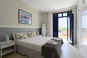Habitación de hotel con cama, mesita de noche, espejo y vistas al exterior.