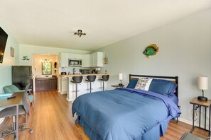 Une chambre d’hôtel moderne dotée d’un grand lit, d’un bureau avec une chaise, d’une kitchenette et d’une salle de bain.